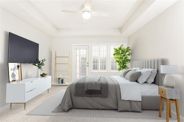 carpeted bedroom featuring a tray ceiling, ceiling fan, and baseboards