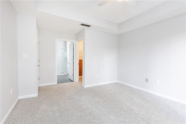 carpeted spare room featuring a ceiling fan, visible vents, and baseboards