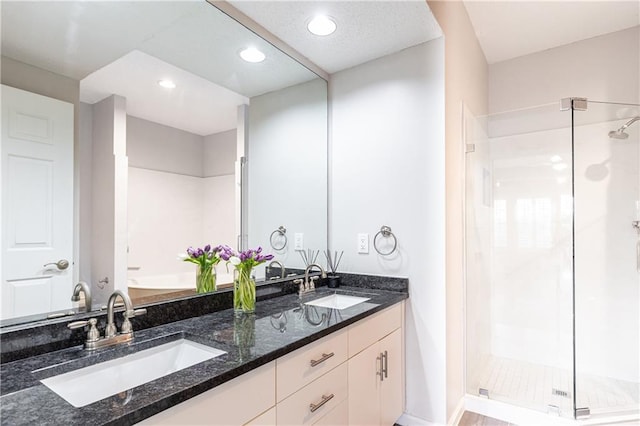 bathroom with double vanity, a stall shower, a sink, and recessed lighting