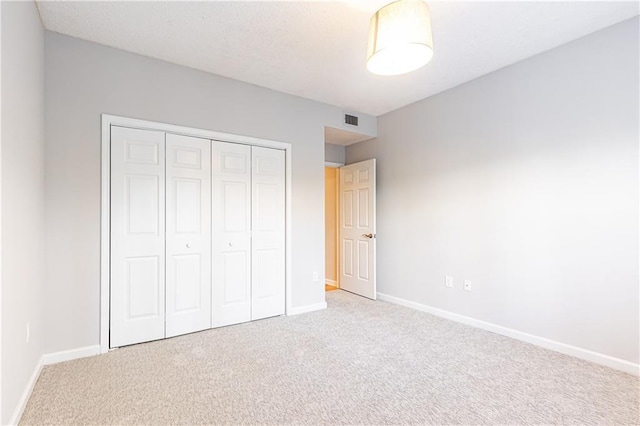 unfurnished bedroom with carpet floors, baseboards, visible vents, and a closet