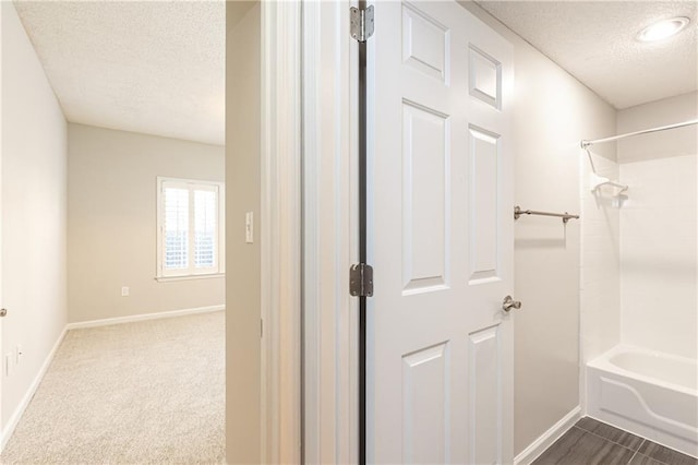 bathroom featuring a textured ceiling, baseboards, and shower / bathtub combination