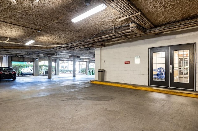 parking garage featuring concrete block wall and french doors