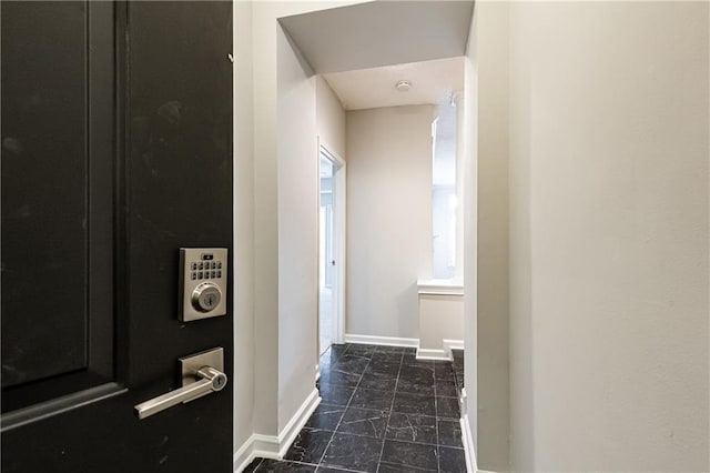 corridor with marble finish floor and baseboards