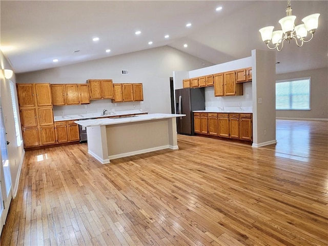 kitchen with high vaulted ceiling, decorative light fixtures, a center island, light hardwood / wood-style floors, and stainless steel refrigerator with ice dispenser