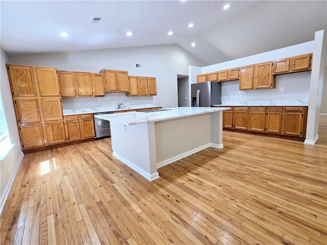 kitchen with stainless steel appliances, a kitchen breakfast bar, a kitchen island, and light wood-type flooring