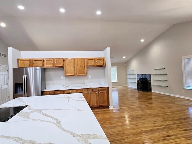 kitchen featuring hardwood / wood-style flooring, a premium fireplace, lofted ceiling, and stainless steel fridge