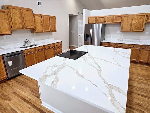 kitchen with dishwashing machine, lofted ceiling, sink, light hardwood / wood-style floors, and stainless steel fridge with ice dispenser