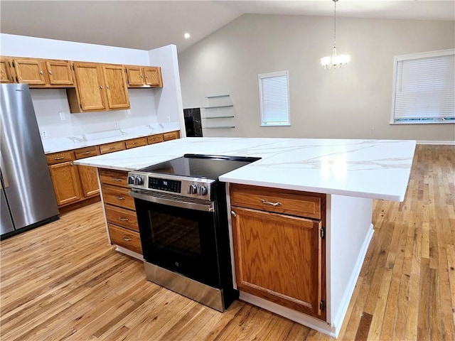 kitchen with hanging light fixtures, stainless steel appliances, a kitchen island, vaulted ceiling, and light wood-type flooring