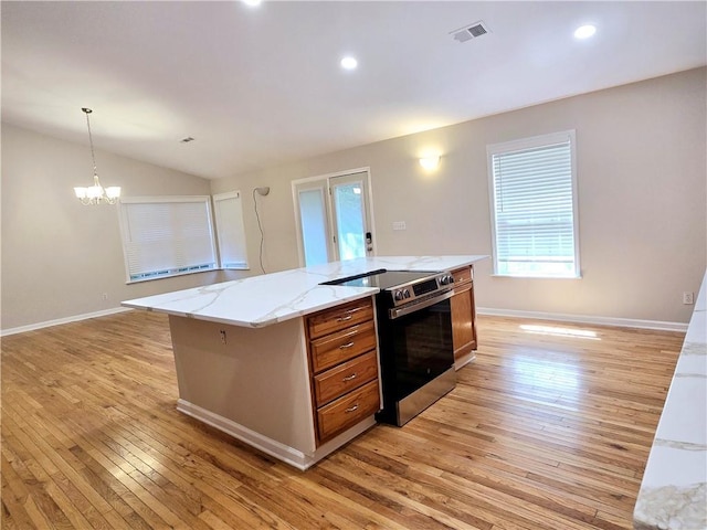 kitchen featuring light stone counters, stainless steel electric range oven, a center island, hanging light fixtures, and light wood-type flooring