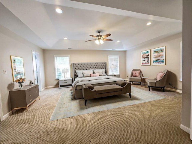 carpeted bedroom featuring a raised ceiling and ceiling fan