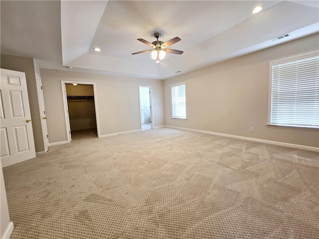 carpeted spare room featuring ceiling fan and a raised ceiling