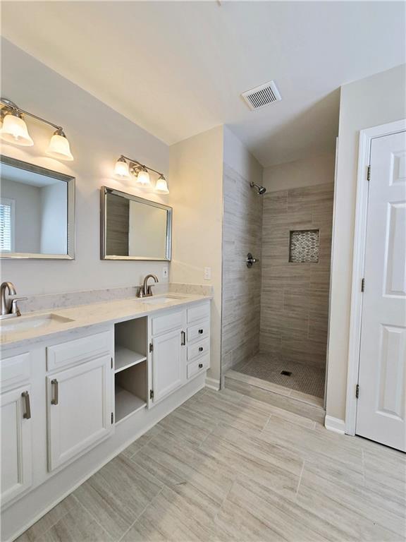 bathroom with vanity and tiled shower