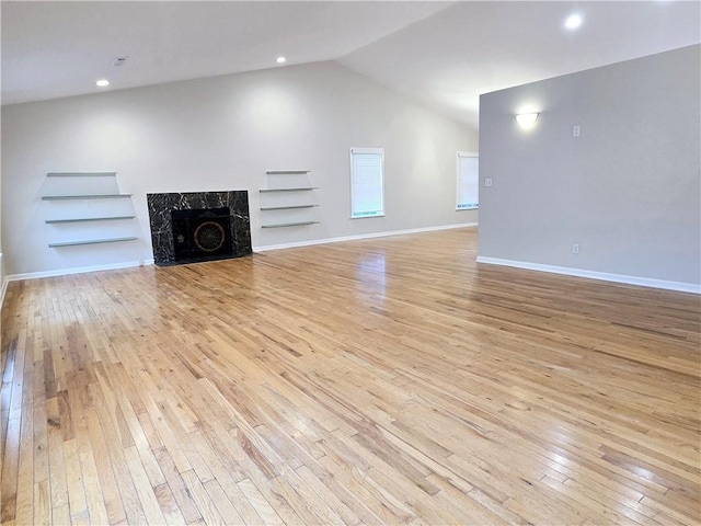 unfurnished living room featuring lofted ceiling, a fireplace, and light wood-type flooring