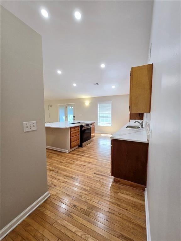 kitchen with kitchen peninsula, sink, and light hardwood / wood-style flooring