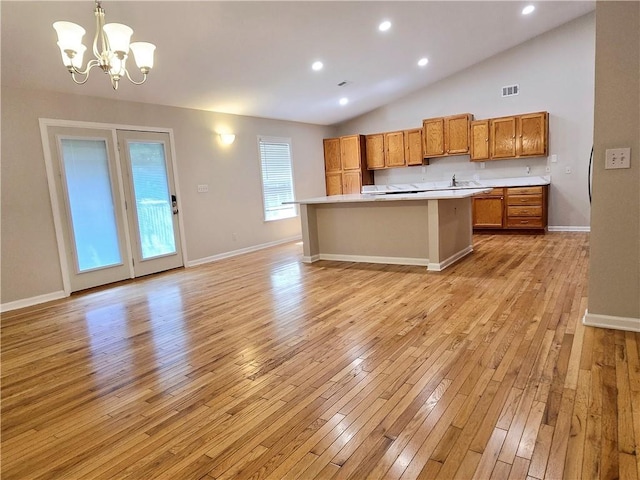 kitchen with a center island, vaulted ceiling, hanging light fixtures, light hardwood / wood-style flooring, and a notable chandelier