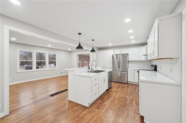 kitchen with appliances with stainless steel finishes, tasteful backsplash, sink, decorative light fixtures, and white cabinets