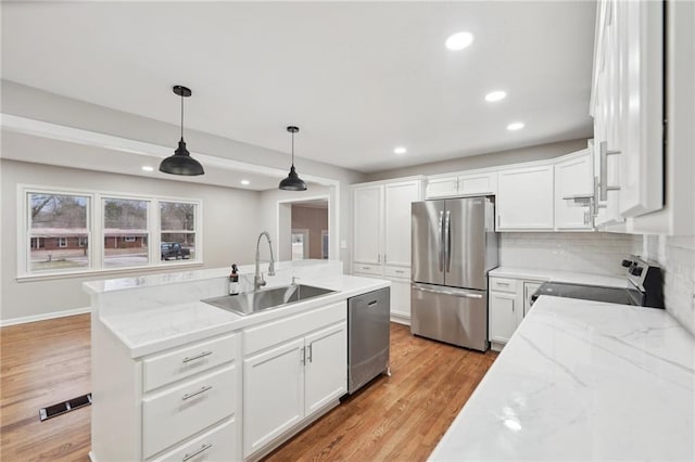 kitchen featuring sink, stainless steel appliances, light stone counters, decorative light fixtures, and white cabinets