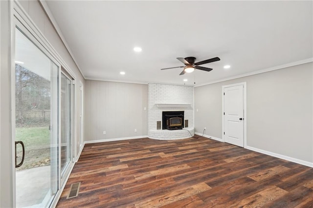 unfurnished living room featuring a wood stove, ceiling fan, dark hardwood / wood-style flooring, and crown molding