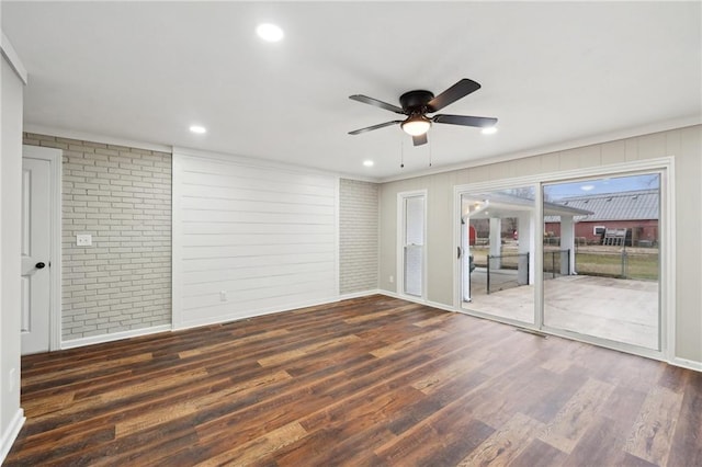 unfurnished room with dark hardwood / wood-style flooring, ceiling fan, and brick wall