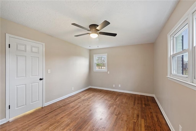 empty room with a textured ceiling, dark hardwood / wood-style flooring, and ceiling fan