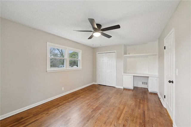 unfurnished bedroom featuring ceiling fan, light hardwood / wood-style floors, and a closet