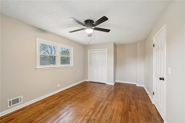 unfurnished bedroom featuring hardwood / wood-style flooring, ceiling fan, a textured ceiling, and a closet