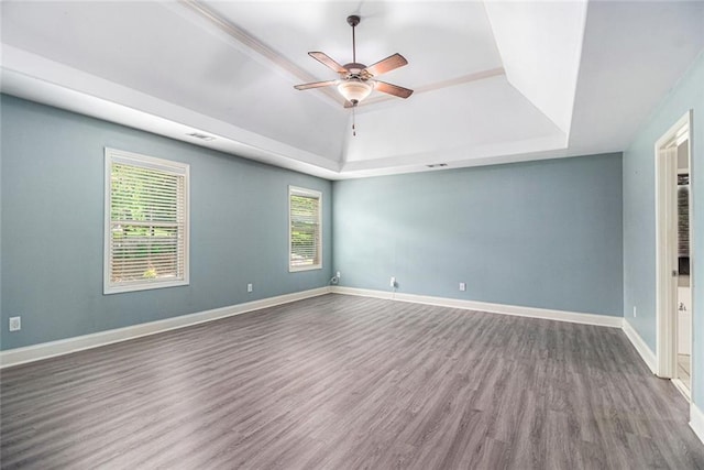 unfurnished room featuring a tray ceiling, wood finished floors, ceiling fan, and baseboards