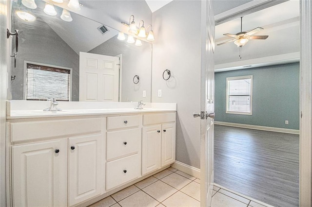 bathroom with tile patterned flooring, ceiling fan, double vanity, baseboards, and vaulted ceiling