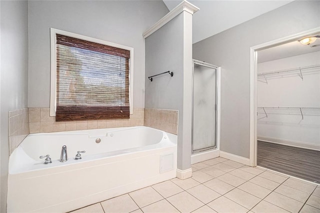 bathroom with tile patterned flooring, a stall shower, a spacious closet, a bath, and baseboards