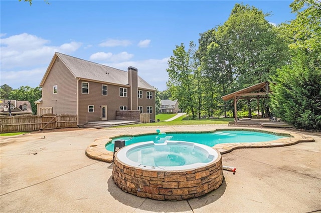 view of pool featuring a pool with connected hot tub, a patio area, a gazebo, and fence