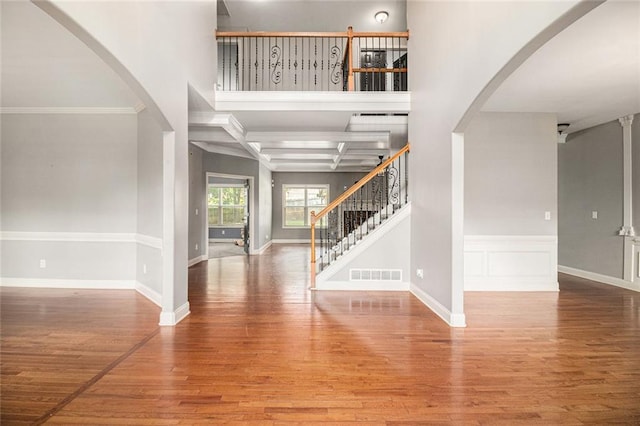 entryway featuring wood finished floors, stairway, arched walkways, ornamental molding, and baseboards