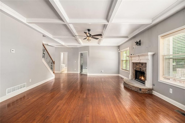 unfurnished living room with stairway, a stone fireplace, ceiling fan, hardwood / wood-style floors, and baseboards