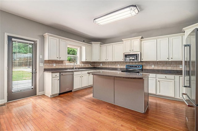 kitchen featuring stainless steel appliances, tasteful backsplash, a sink, and light wood-style floors