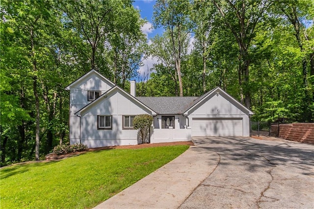 view of front of home featuring a front yard, a chimney, concrete driveway, an attached garage, and fence
