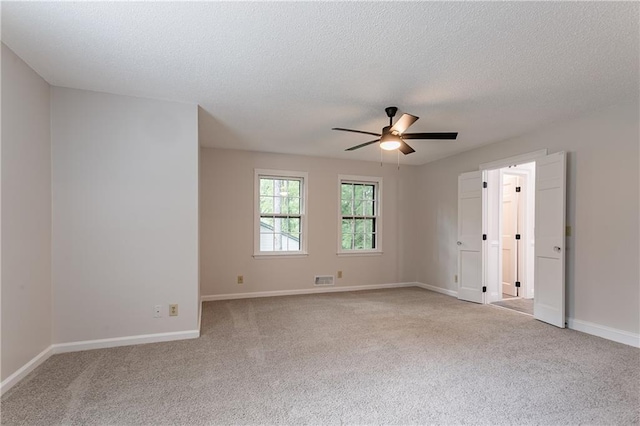 unfurnished room featuring a ceiling fan, a textured ceiling, light carpet, and baseboards