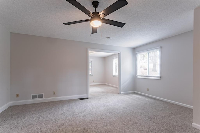 spare room featuring a textured ceiling, visible vents, and carpet floors