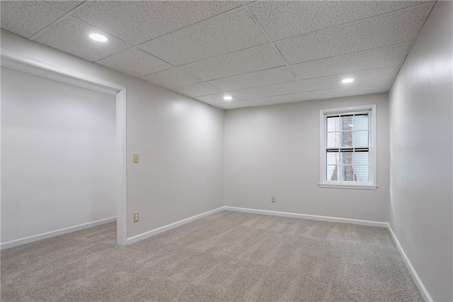 carpeted empty room featuring baseboards, recessed lighting, and a drop ceiling