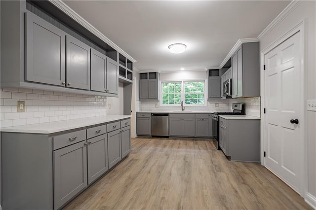 kitchen with decorative backsplash, open shelves, light wood-style floors, stainless steel appliances, and gray cabinets