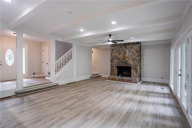 unfurnished living room with stairway, beam ceiling, ceiling fan, baseboards, and wood finished floors