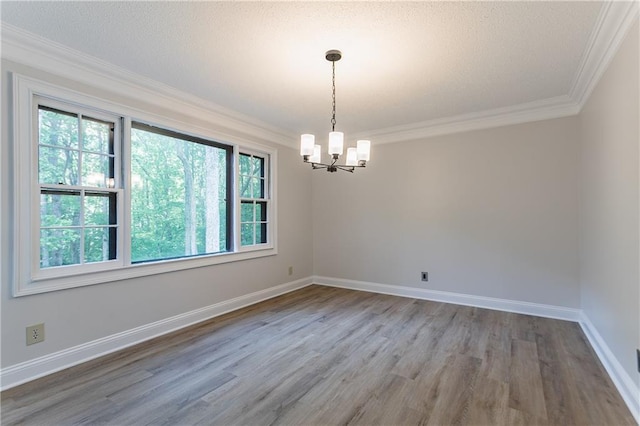 unfurnished room with ornamental molding, wood finished floors, a notable chandelier, and baseboards