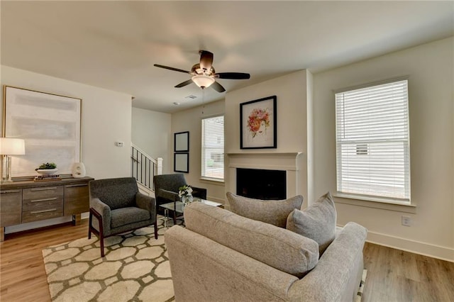 living room with plenty of natural light, ceiling fan, and light wood-type flooring