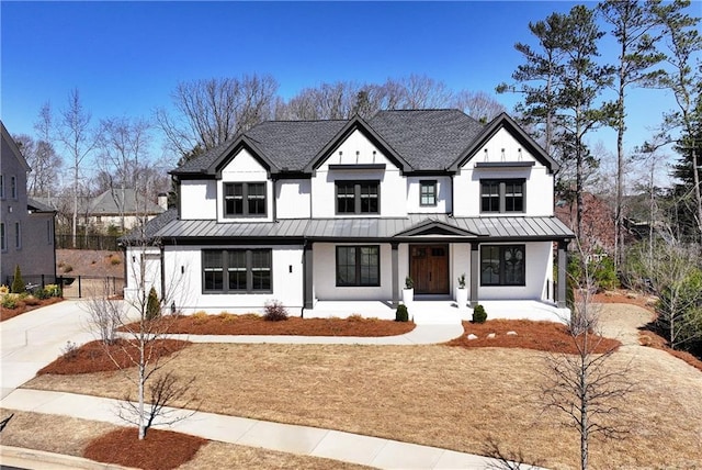 modern farmhouse with fence, concrete driveway, covered porch, metal roof, and a standing seam roof