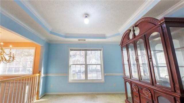 interior space featuring an inviting chandelier, a tray ceiling, and crown molding