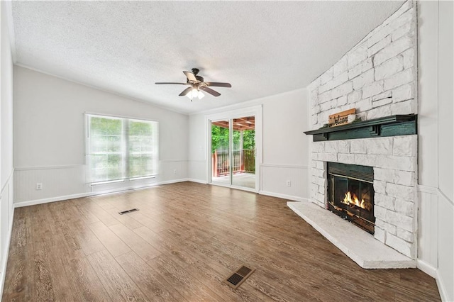 6670 George Ct, Cumming, GA 30041 - unfurnished living room with a ceiling fan, a textured ceiling, wood finished floors, a stone fireplace, and a wainscoted wall