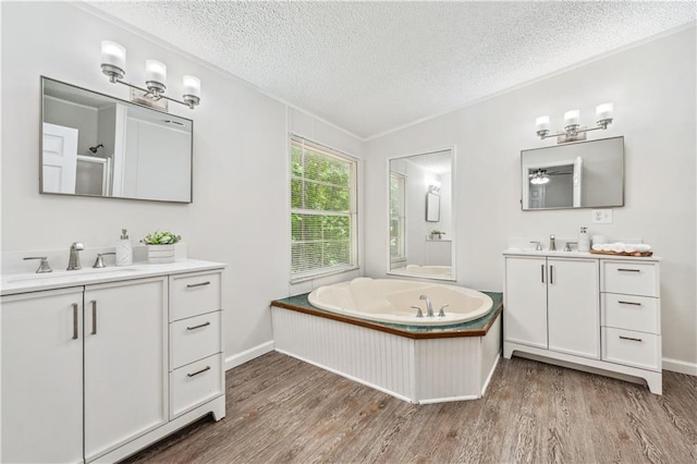 6670 George Ct, Cumming, GA 30041 - full bath with wood finished floors, a textured ceiling, two vanities, a garden tub, and baseboards