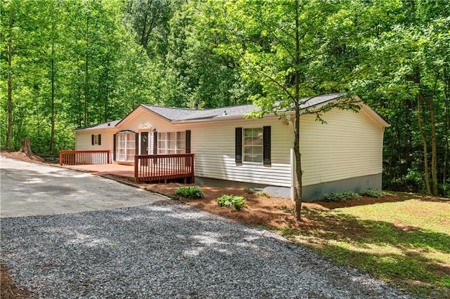 6670 George Ct, Cumming, GA 30041 - view of front facade featuring a deck, a forest view, and driveway