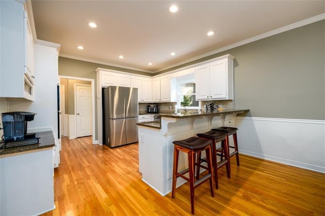 1304 Carrington Way, Lawrenceville, GA 30044 - kitchen with freestanding refrigerator, crown molding, a peninsula, white cabinets, and a kitchen bar