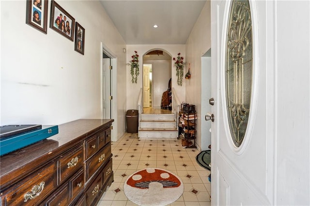 foyer with arched walkways, light tile patterned floors, and stairway