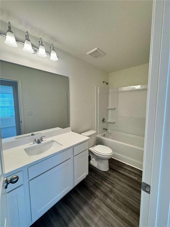 full bath featuring visible vents, toilet, vanity, shower / tub combination, and wood finished floors