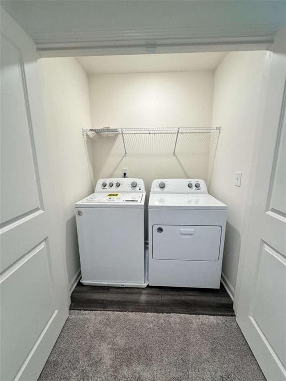 clothes washing area featuring laundry area, dark wood-type flooring, washing machine and dryer, and baseboards